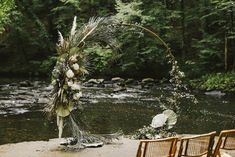 an outdoor ceremony setup with flowers and greenery on the ground next to a river