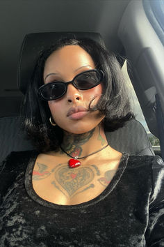 a woman with black hair and tattoos in a car