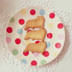 two cookies shaped like dogs on a plate with polka dot doily and lace around the edge