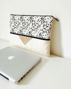 a laptop computer sitting on top of a white table next to a pillow and purse