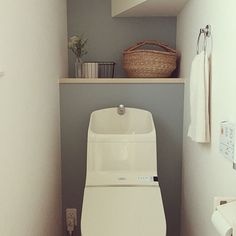 a white toilet sitting in a bathroom next to a shelf with towels and baskets on it