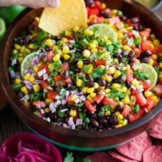 a wooden bowl filled with black beans, corn and avocado salsa next to tortilla chips