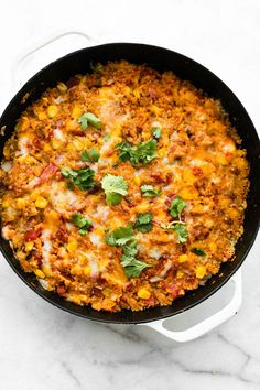 a skillet filled with mexican food and garnished with cilantro leaves