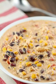 a bowl of soup with beans, corn and other toppings on a red and white table cloth