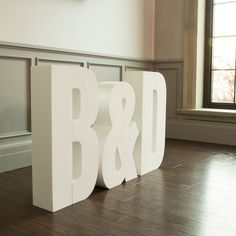 the letters b and d are made out of plywood planks in front of a window