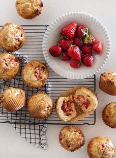 strawberries and muffins on a cooling rack next to a bowl of strawberries