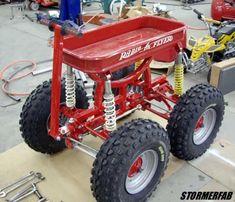 a red wagon sitting on top of a wooden table next to other tools and equipment