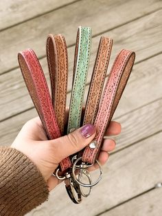 a person holding several key chains in their hand on a wooden decking area with wood planks behind them