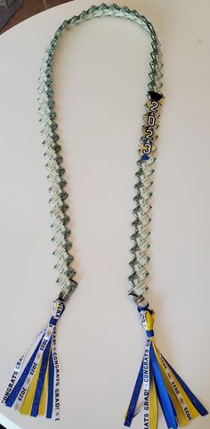 a necklace made out of glass beads with ribbons hanging from it's sides on a table