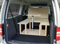 the back end of a van with tables in it