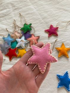 a hand holding a star shaped ornament in front of several different colored stars