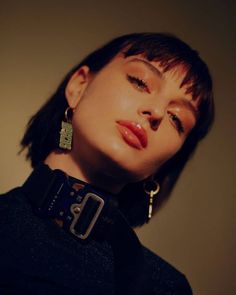 a woman with her eyes closed wearing large earrings and a black sweater is posing for the camera