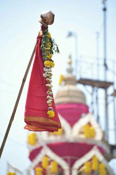 a red cloth hanging from a pole next to a building with yellow and white flowers