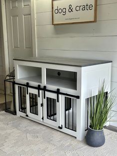 a dog and crate sitting on the floor next to a potted plant in front of a door