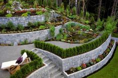 an outdoor garden with stone walls and steps leading up to the water feature in the center