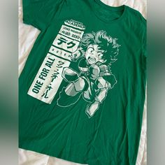 a green t - shirt with an anime character on the front and white lettering that says,