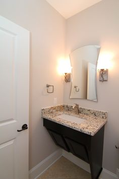 a bathroom with a sink, mirror and lights on the side of the door way