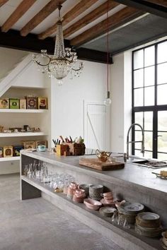 an open kitchen with lots of dishes on the counter and chandelier hanging from the ceiling