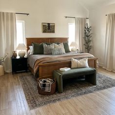 a large bed sitting on top of a wooden floor next to two lamps and windows