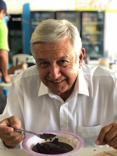 an older man sitting at a table with a plate of food in front of him