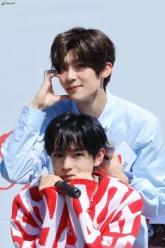 two young men sitting next to each other with microphones in their hands and one on his head