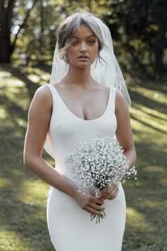 a woman in a white wedding dress holding a bouquet of baby's breath flowers