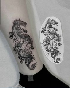 a woman's leg with a dragon and flowers tattoo on the left side of her arm