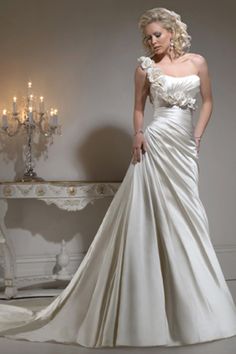 a woman in a white wedding dress standing next to a table and chandelier