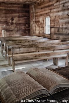 an open book sitting on top of a table next to pews in a church