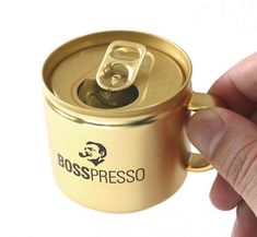 a hand is holding a gold can with the lid open