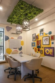 a white table with four chairs under a green plant hanging from it's ceiling