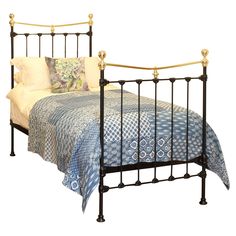 a metal bed frame with blue and white bedspread on top of the bed