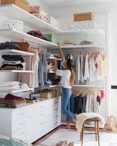 a woman standing in front of a white closet filled with clothes and other clothing items