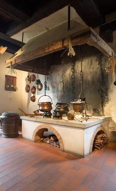 an old fashioned kitchen with pots and pans hanging from the ceiling