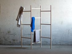 three towels are hanging on a rack in an empty room with concrete walls and cement flooring