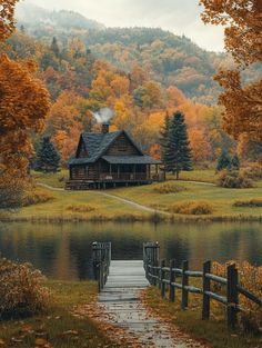 a cabin sits on the edge of a lake surrounded by autumn foliage and trees, with a dock leading to it