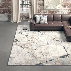 a living room with a sectional couch, rug and brick wall in the back ground