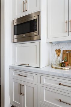 a kitchen with white cabinets and stainless steel microwave