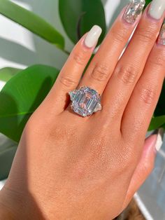 a woman's hand with a diamond ring on top of her finger and white nail polish