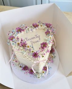 a heart shaped cake in a box with flowers on the side and writing'twenty nine '