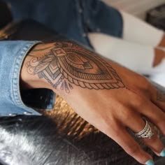 a woman's hand with a tattoo on her left arm and the other hand