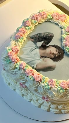 a white cake with pink, yellow and green frosting in the shape of a woman's face