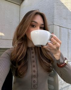 a woman holding a coffee cup up to her face