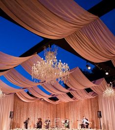 an elegant wedding setup with chandeliers and white drapes