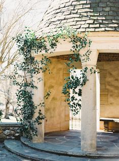 an outdoor gazebo with green vines growing on it's roof and stone steps