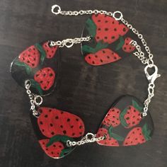 a close up of a bracelet made out of plastic strawberries on a wooden table