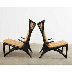 a pair of lounge chairs made out of black wood with yellow leather upholsters