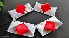 an origami wreath made out of red and white fabric on a black surface