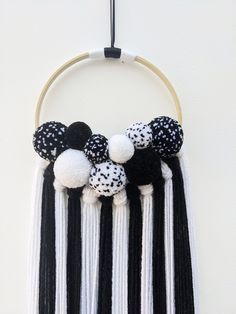 a black and white wall hanging with pom poms