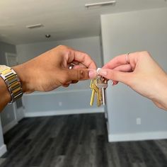 two hands holding keys in an empty room